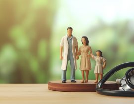 Small wooden figures of mom dad and kid on a doctor s table with a stethoscope Family health care and regular checkup concept Blurred background for me
